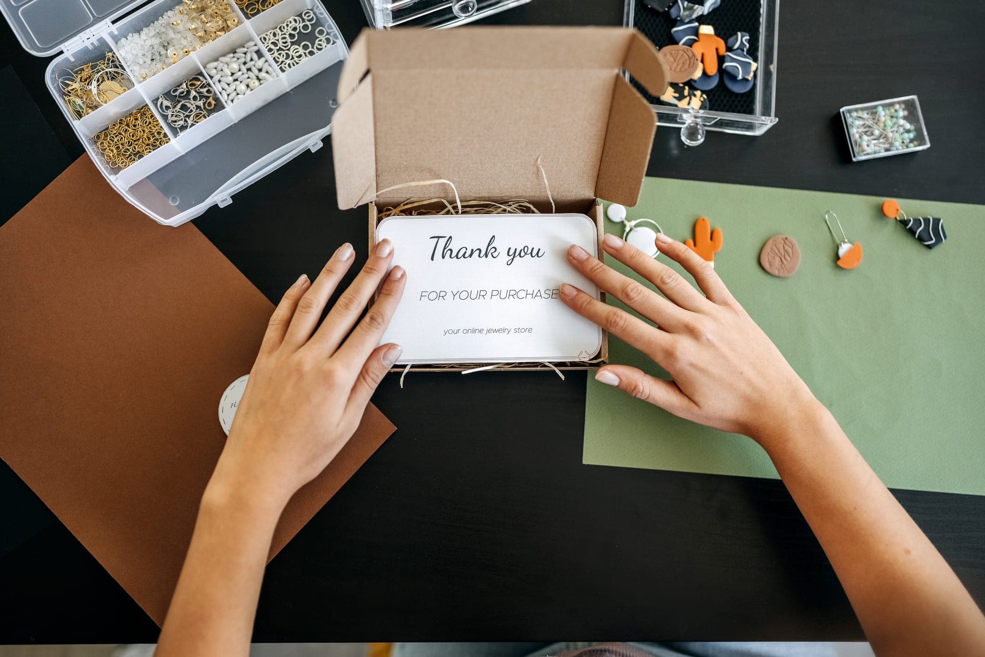Hands packing a parcel with a handwritten thank-you card on top
