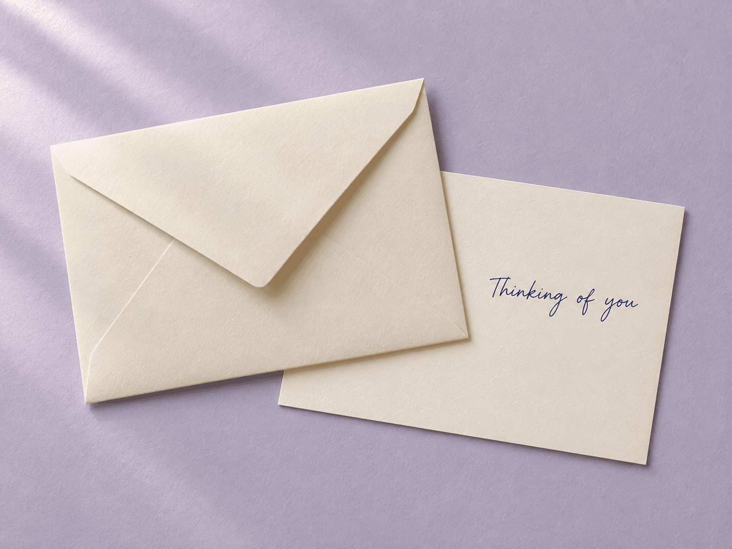 Ivory envelope beside a postcard that reads Thinking of you
