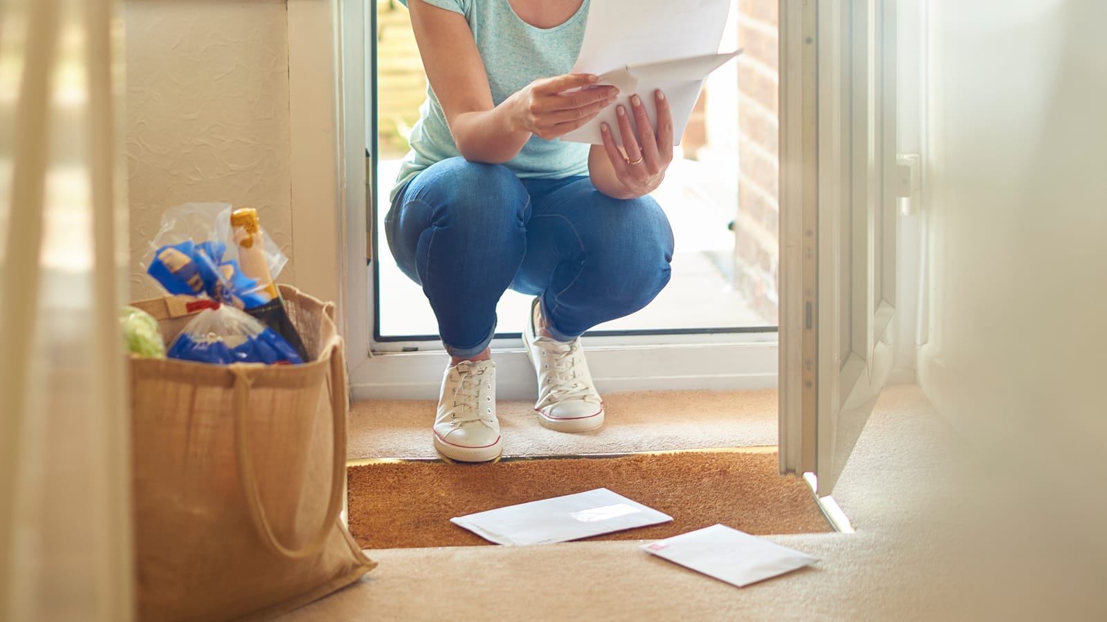 A homeowner at her front door reading a handwritten thank-you card from the roofing crew that just finished her house