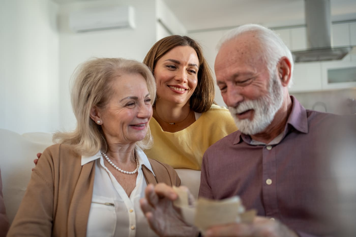 A retired couple on their sofa reading a handwritten thank-you card from their financial advisor, envelope on the table