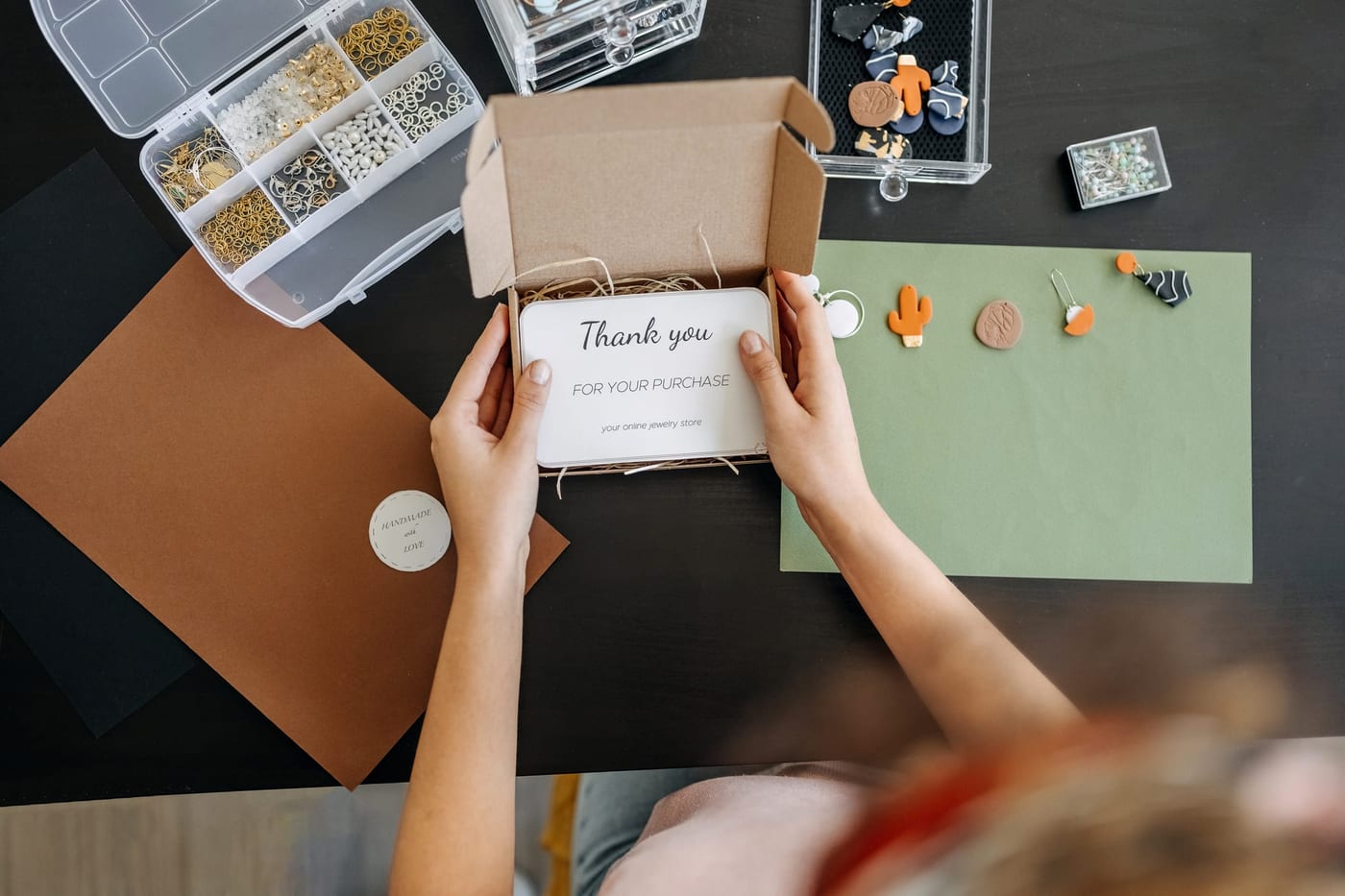 A person holding a handwritten thank-you card above an open parcel, reading it before unpacking the product