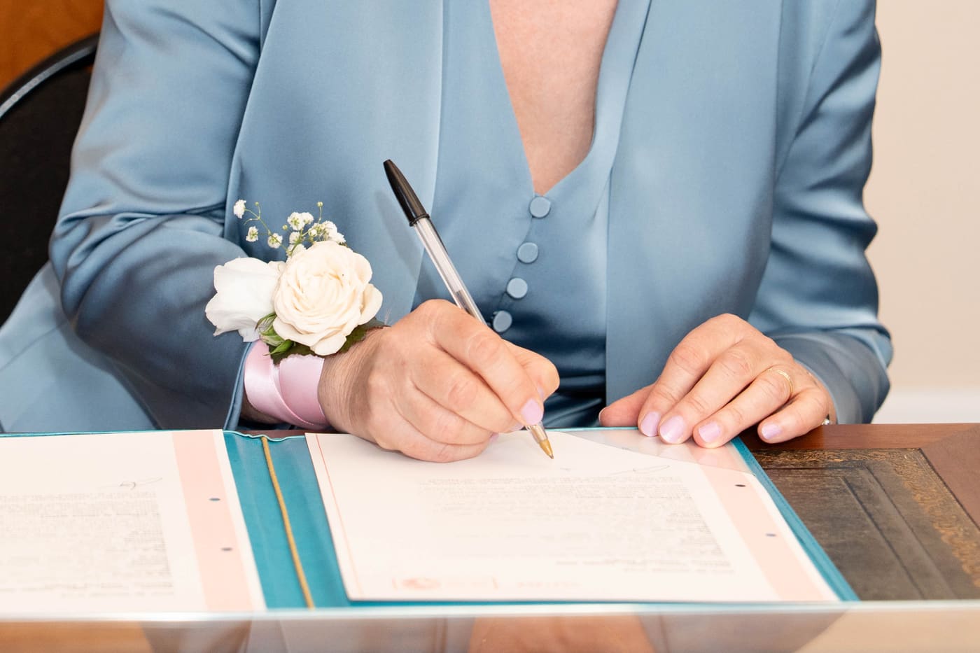 A florist at her workbench writing a card by hand for a newly married couple, leftover eucalyptus and ribbon beside her